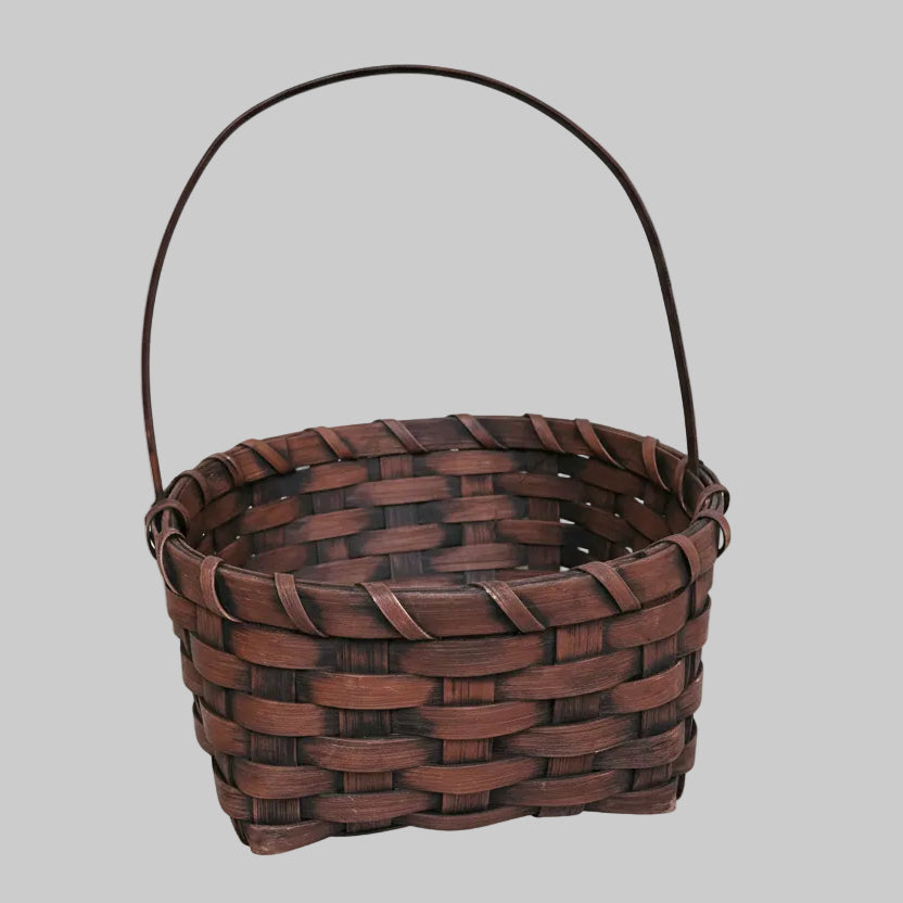 Woven brown basket with a handle on a wooden surface