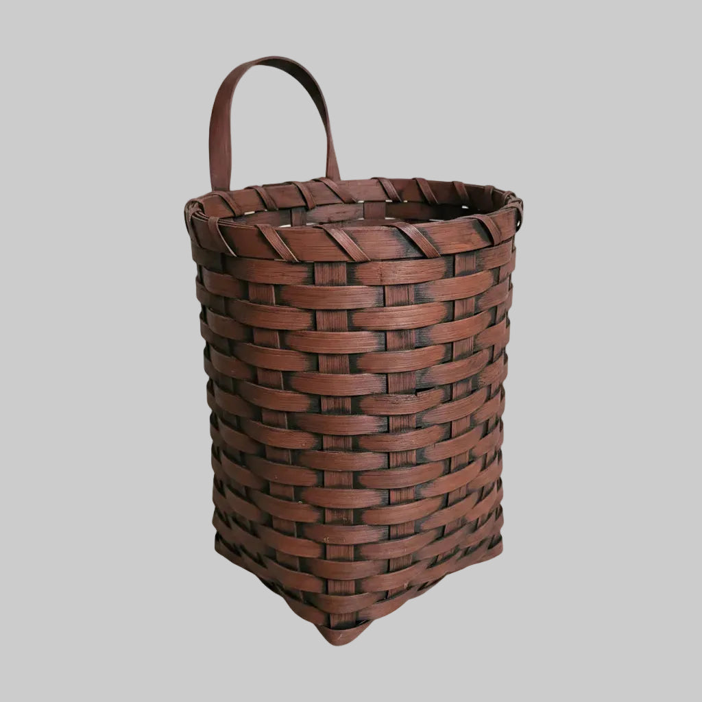Woven brown basket with a handle on a grey background