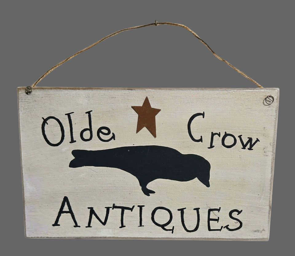 Wooden sign with 'Olde Crow Antiques' text and crow silhouette on a wooden background