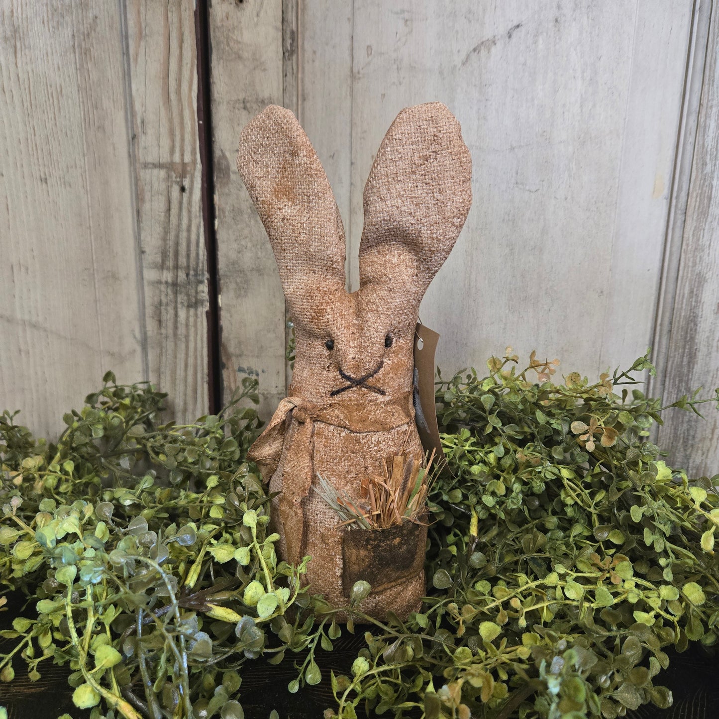 Textured brown bunny figure with greenery on a wooden surface