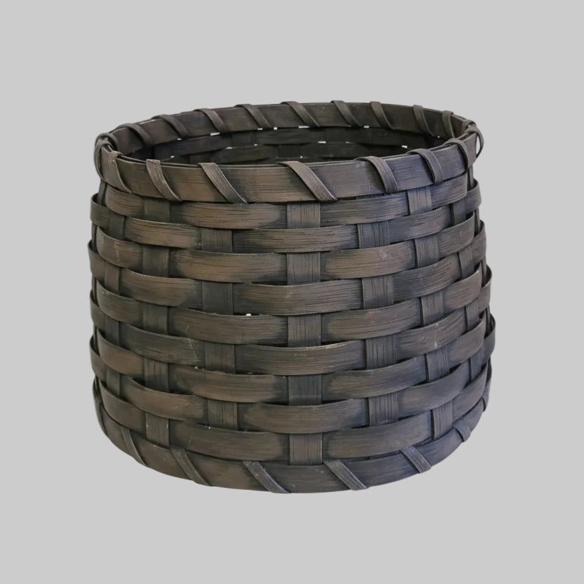 A brown woven basket tree collar on a patterned rug.