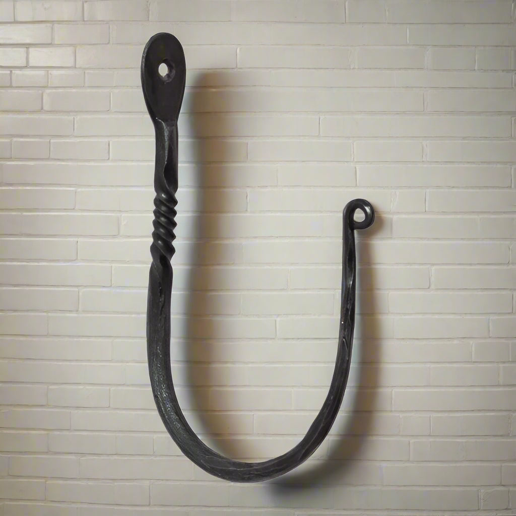 A twisted wrought iron wall hook with a curved hook and a twisted handle, isolated on a white background.