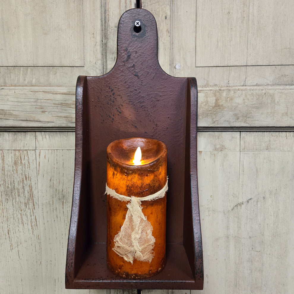 Battery operated candle in a rustic wooden sconce against a wooden wall.