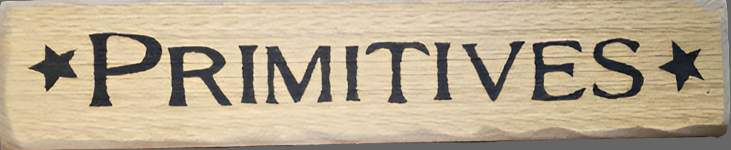 A wooden sign with the word 'Primitives' written in black on a cream background color, surrounded by a star pattern