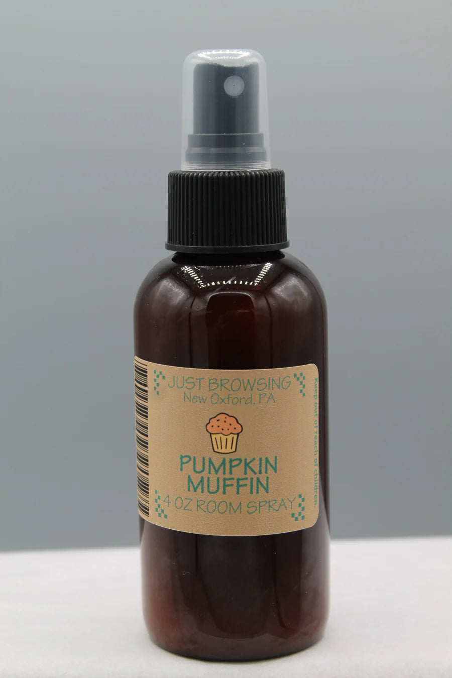 A 4oz bottle of Pumpkin Muffin room spray with a mist spray top. The label features the product name and an image of a cupcake.
