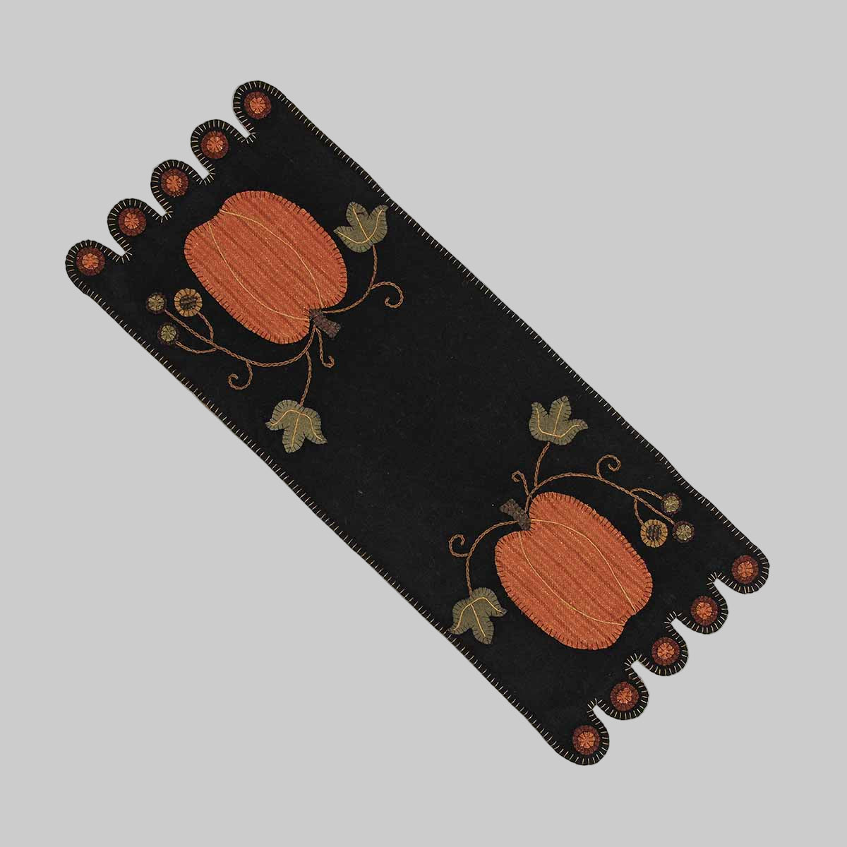 A black table runner with pumpkin designs and leaf patterns, likely made from wool felt.