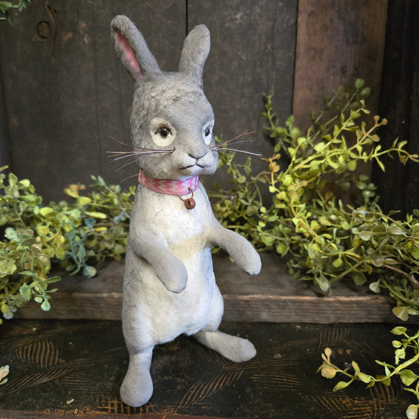 Paper mache rabbit with a wooden background and greenery
