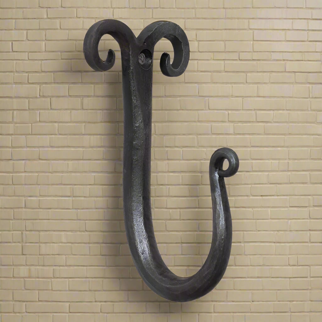 A black wrought iron wall hook with a curled top design.