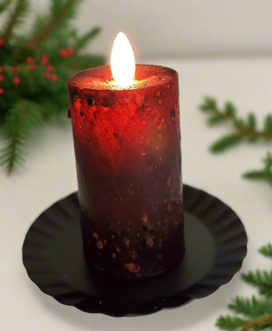 A realistic moving flame mini pillar candle in burgundy color, placed on a black dish.