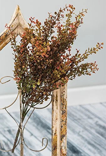 Decorative wreath with autumnal leaves on a rustic wooden stand against a blurred background