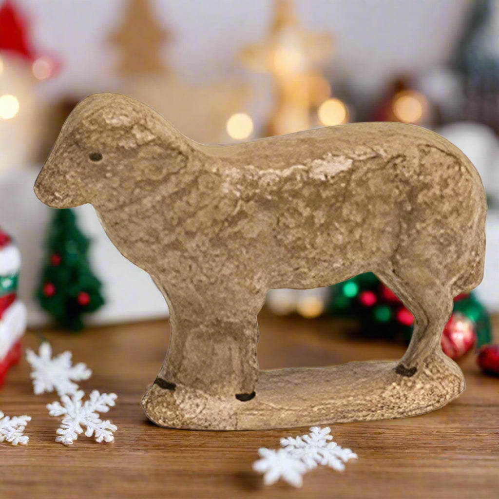 A freestanding resin sculpture of an antique sheep with black painted eyes and hooves.