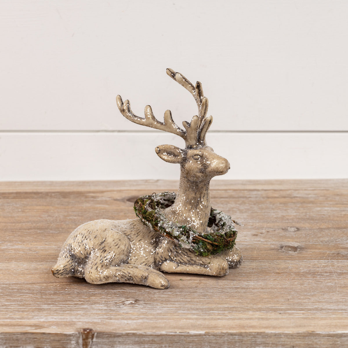 Decorative deer figurine with moss on a wooden surface
