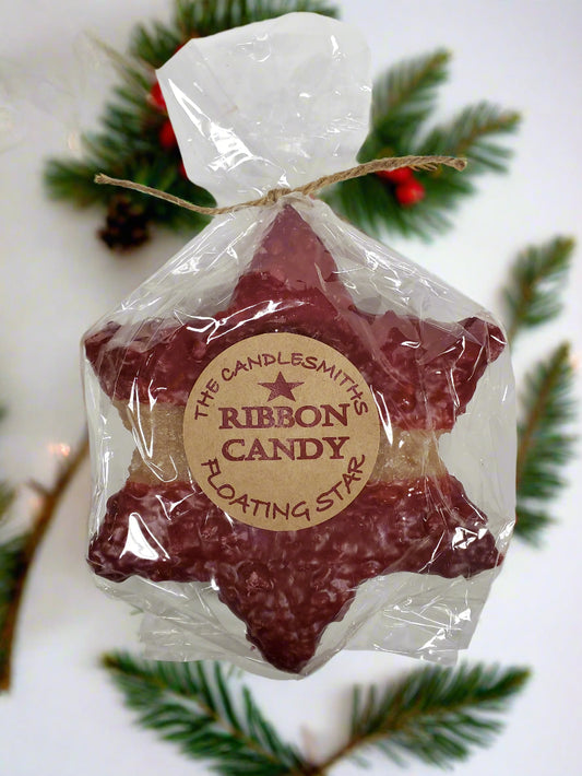 A large red star-shaped floating candle by The Candlesmith, packaged in a clear plastic bag with a label and a string attached to top.