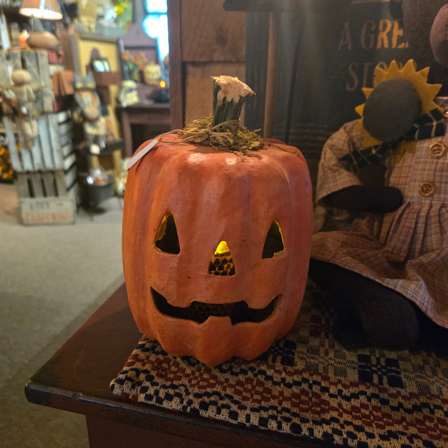 Pumpkin with a carved face on a shelf in a store setting
