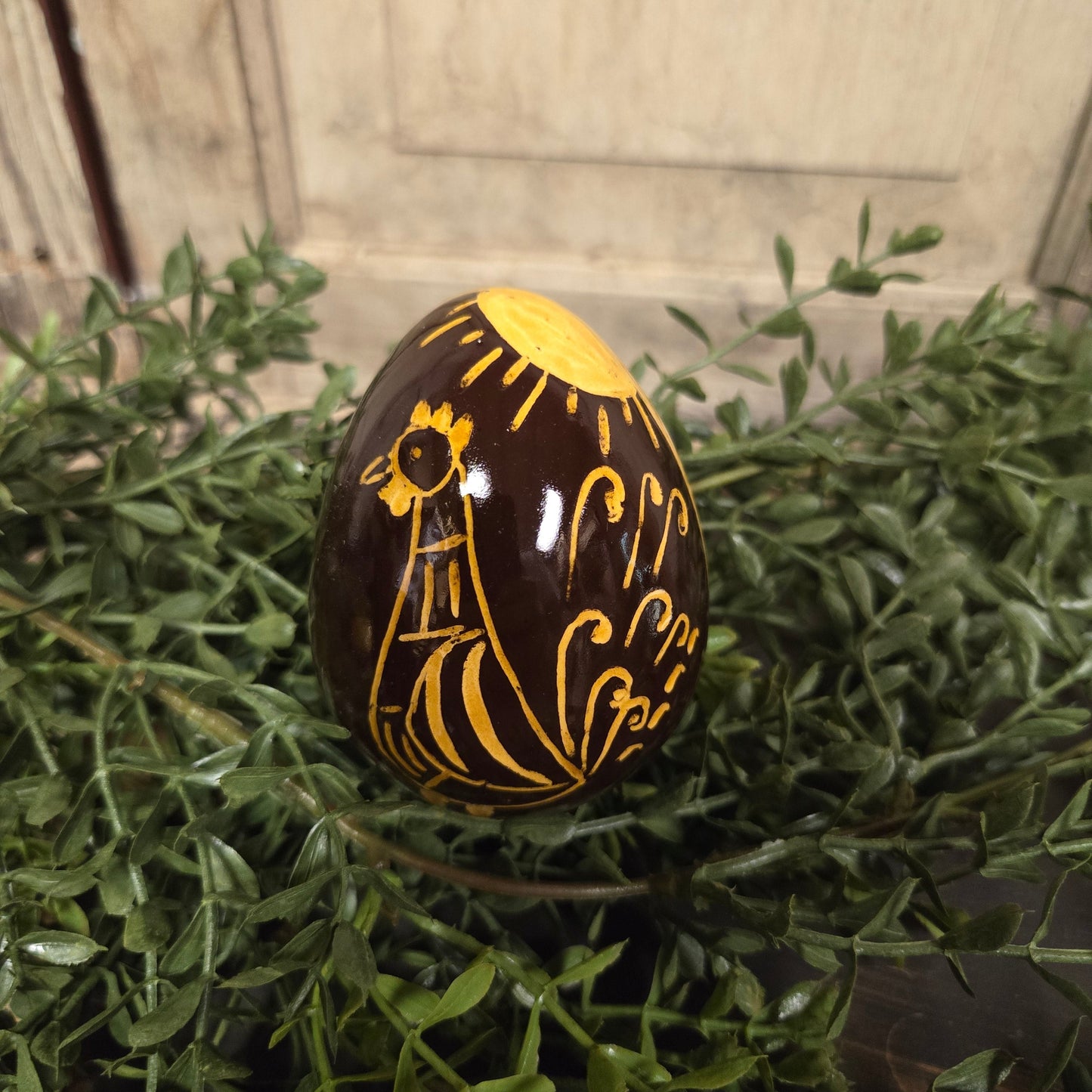 Brown redware egg with yellow glazed rooster and sun motif