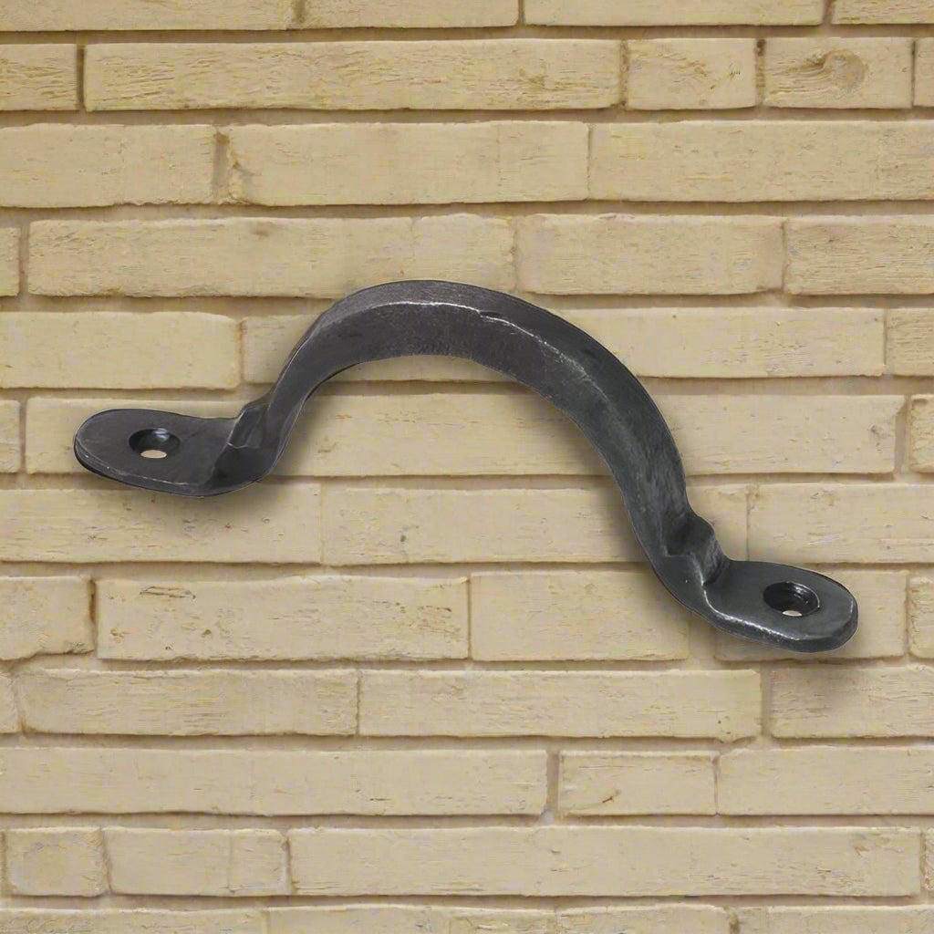 Antique wrought iron cabinet pull handle with a rounded shape and mounting holes, finished in black.