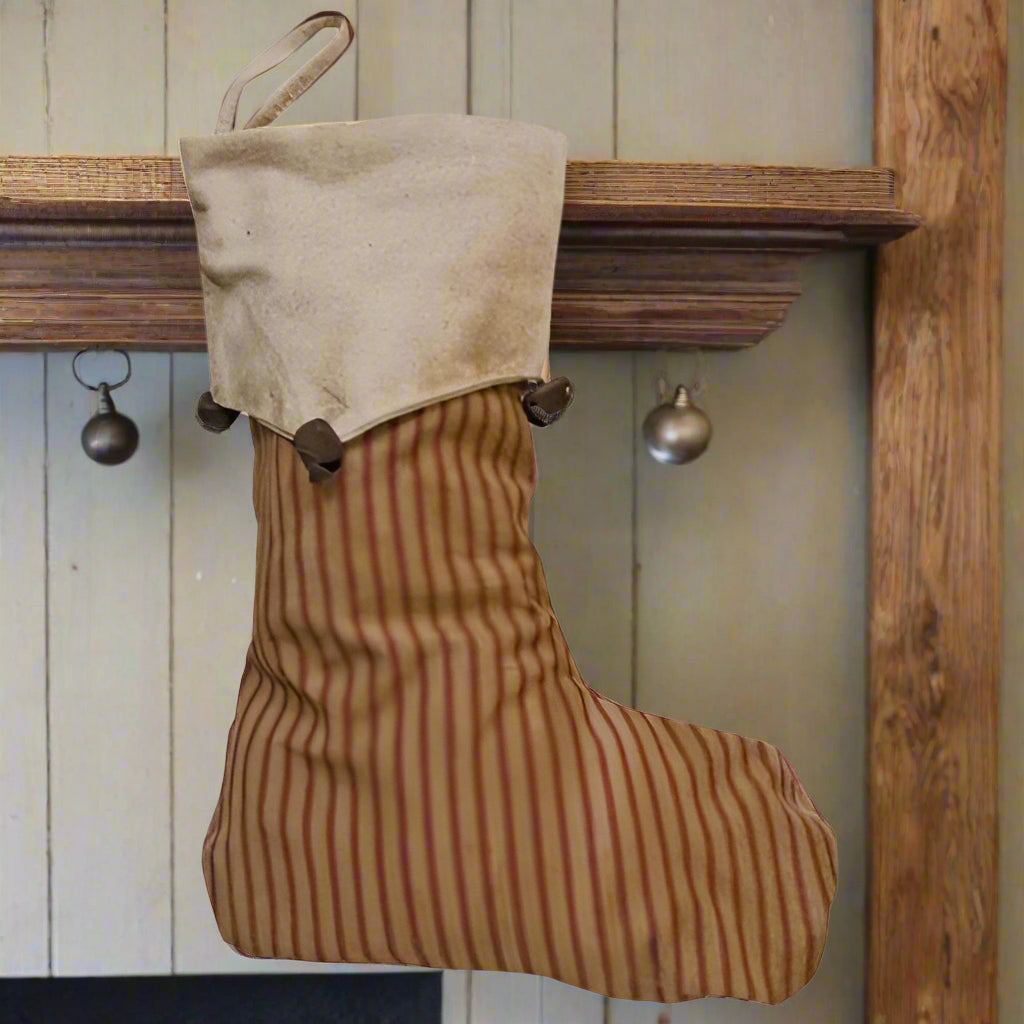 A rustic holiday stocking with a striped pattern, bell accents, and a round shape.