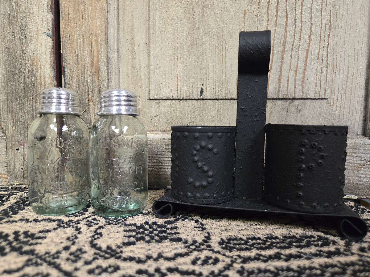 Salt and pepper carrier with two glass salt and pepper shakers on a weathered wood background.