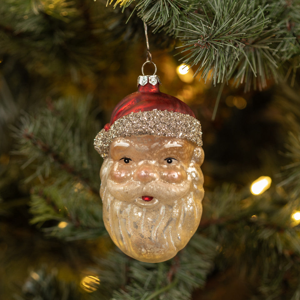 Vintage-style Santa Claus ornament on a Christmas tree with blurred lights in the background