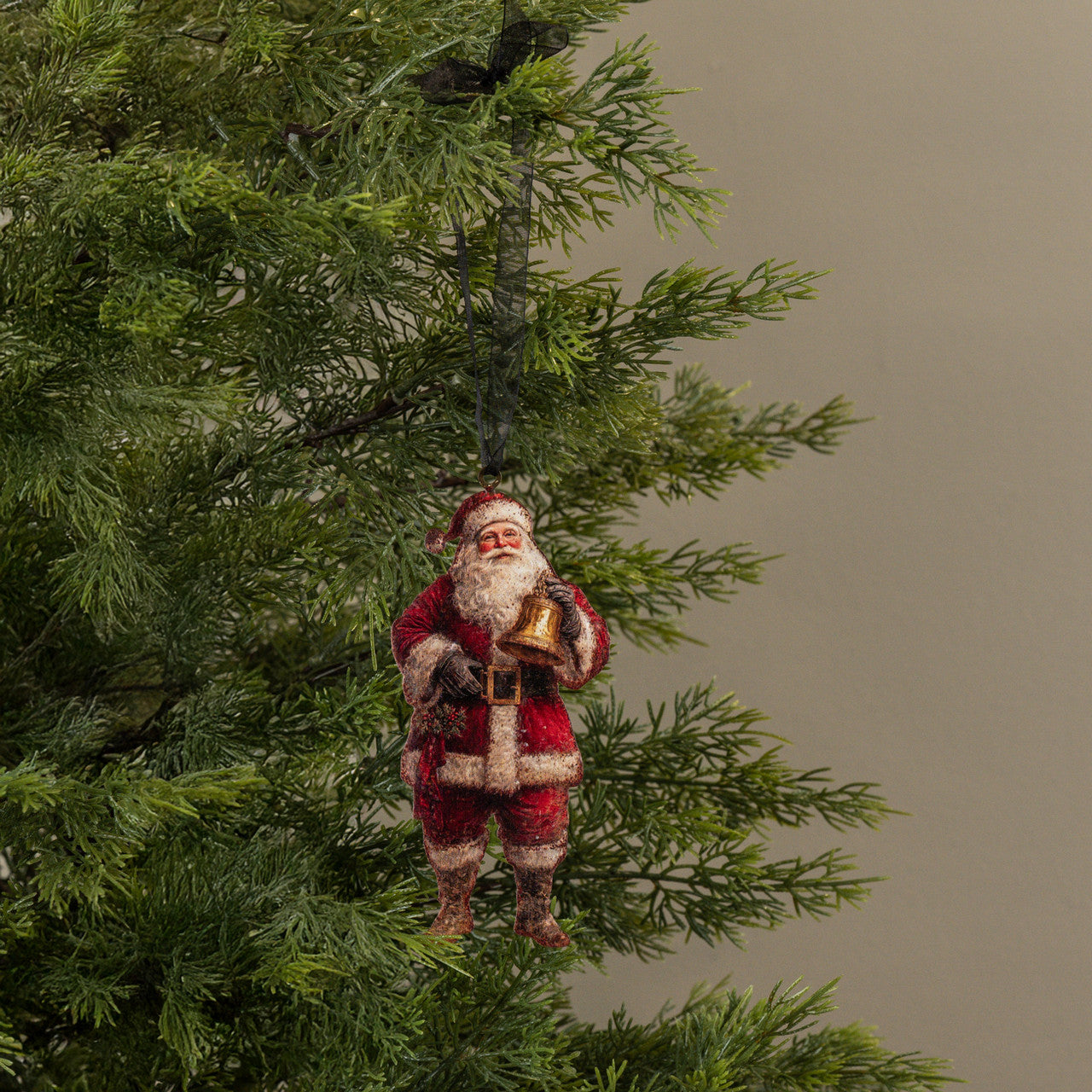 Santa Claus ornament hanging on a Christmas tree with a plain background