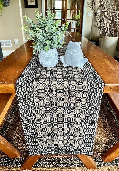 A black and tan geometric patterned place mat on a wooden dining table.