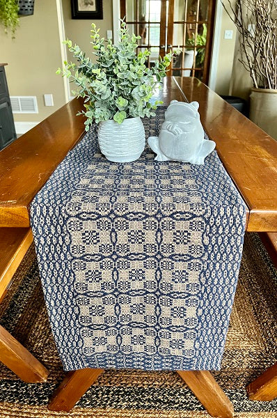Table with a patterned table runner, plant, and decorative item in a home setting.