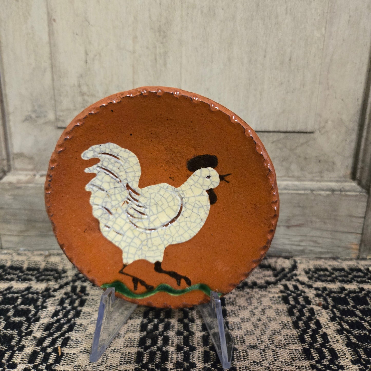 Small round redware plate featuring a white chicken with open beak standing on grass