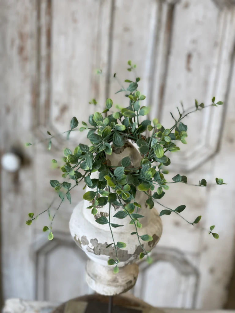 Vase with greenery against a wooden panel background