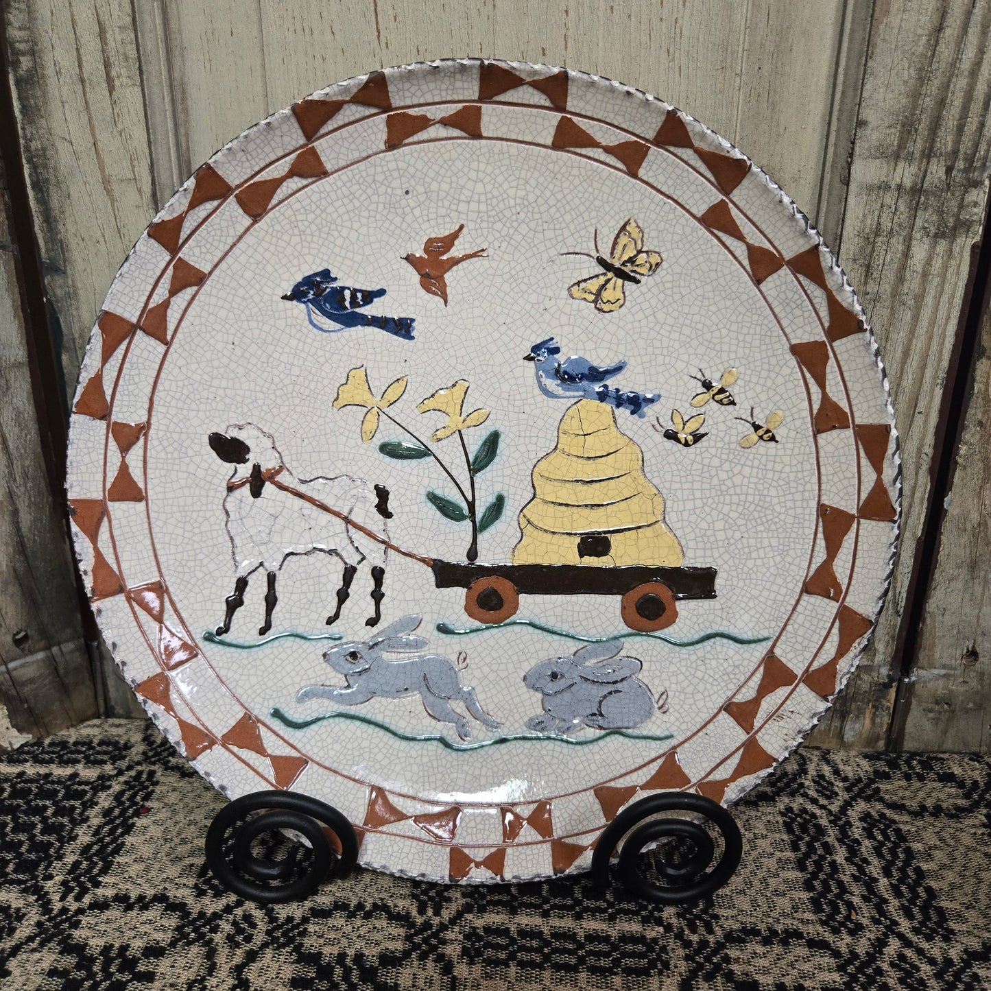 Redware plate with sheep pulling wagon with a bee skep with birds and butterflies flying overhead