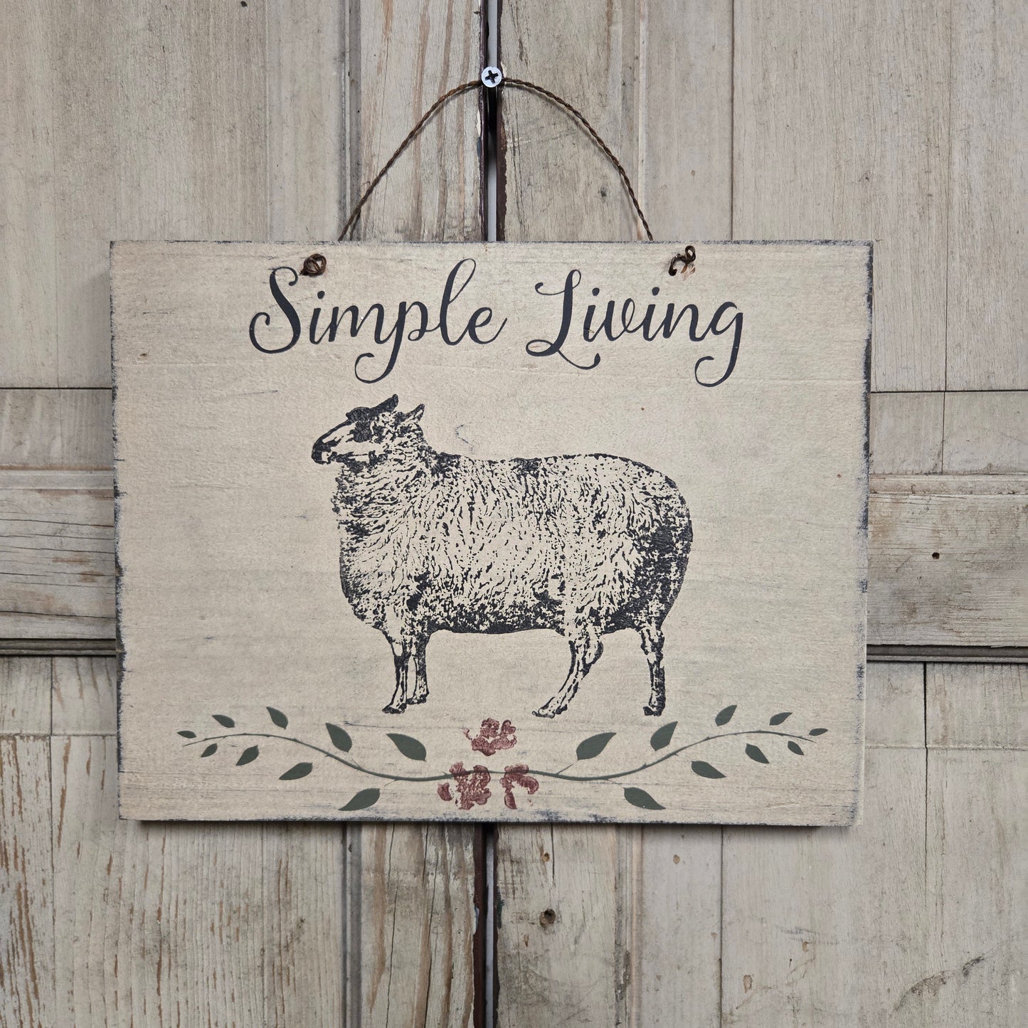 Decorative sign with a sheep illustration and 'Simple Living' text on a wooden background