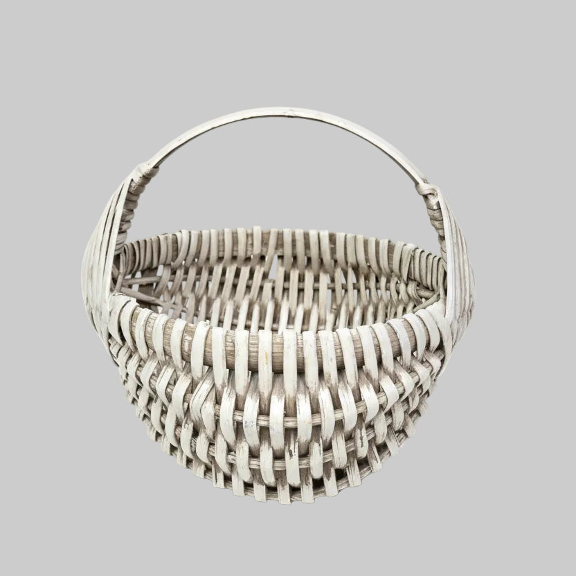 Handwoven basket sitting against a wooden wall with greenery