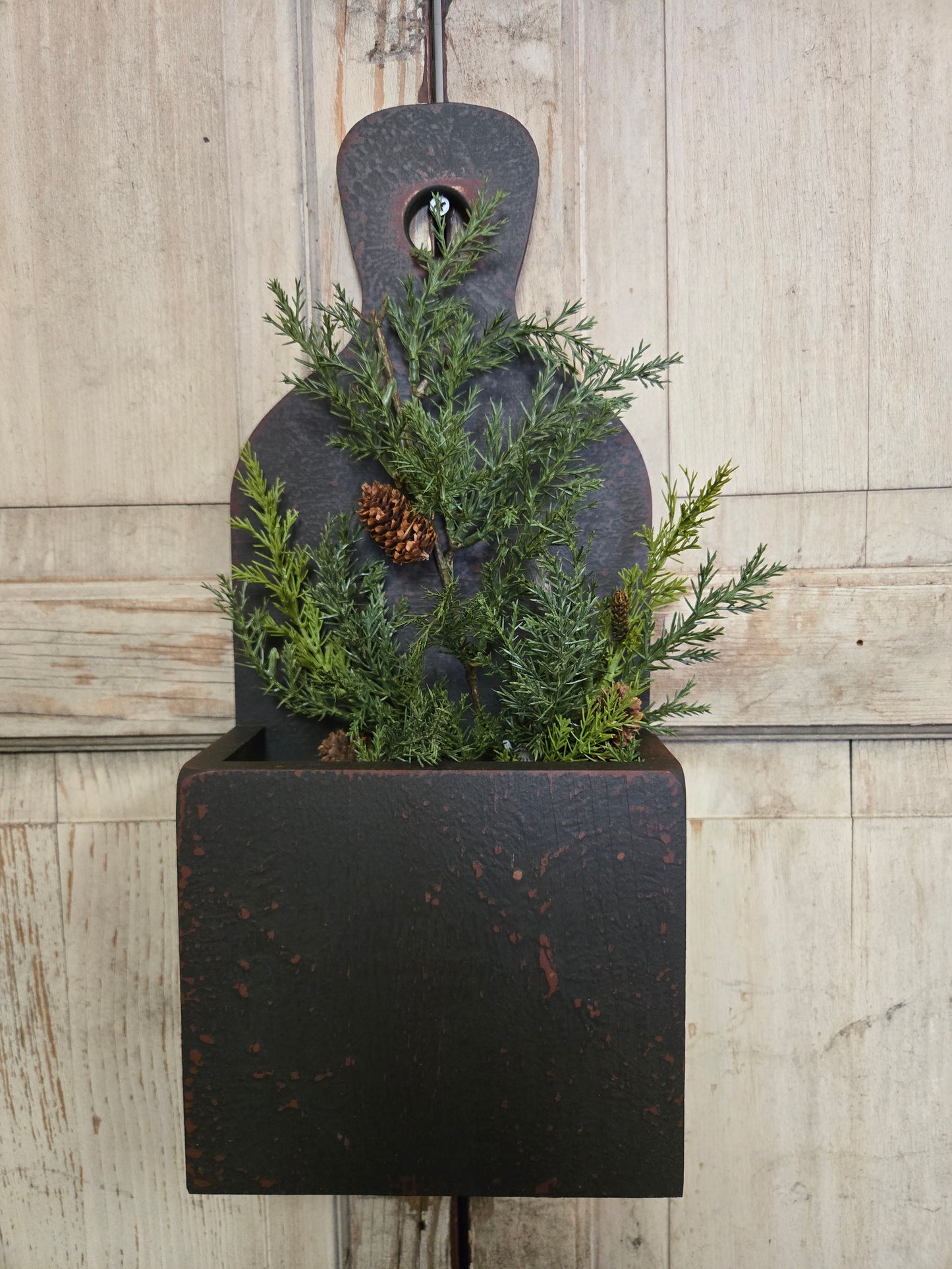 Black cutting board with greenery on a wooden surface