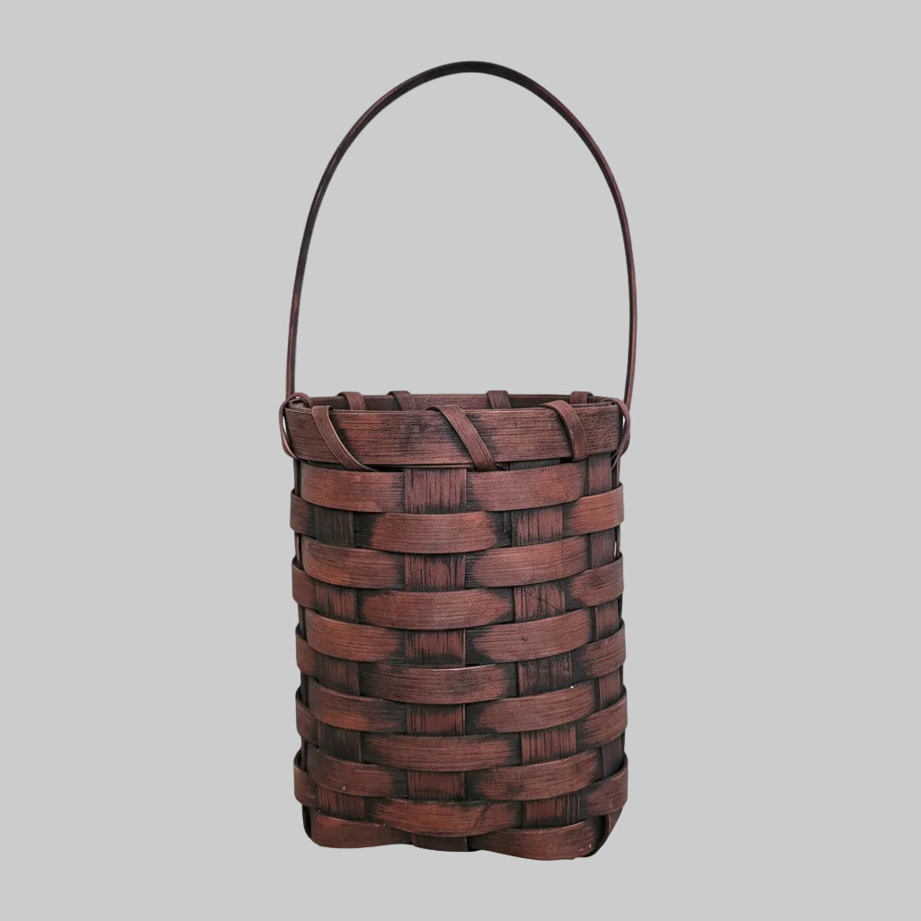 Woven brown basket with greenery on a wooden surface