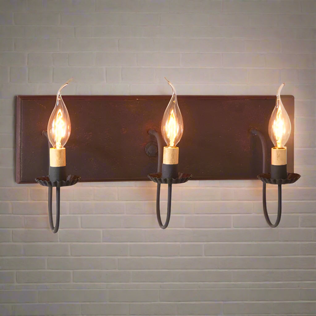 A black vanity light fixture with red stripes, featuring three hanging lights with bulb encasements, designed to be mounted over a mirror.