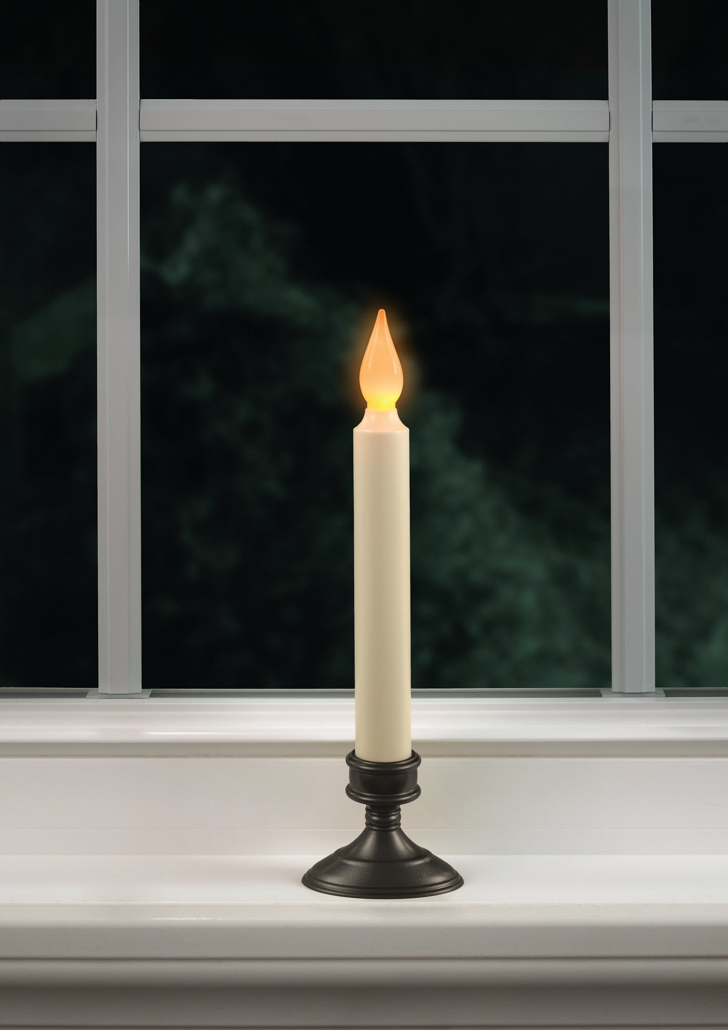 A battery operated window candle with a realistic amber flame displayed on a windowsill.