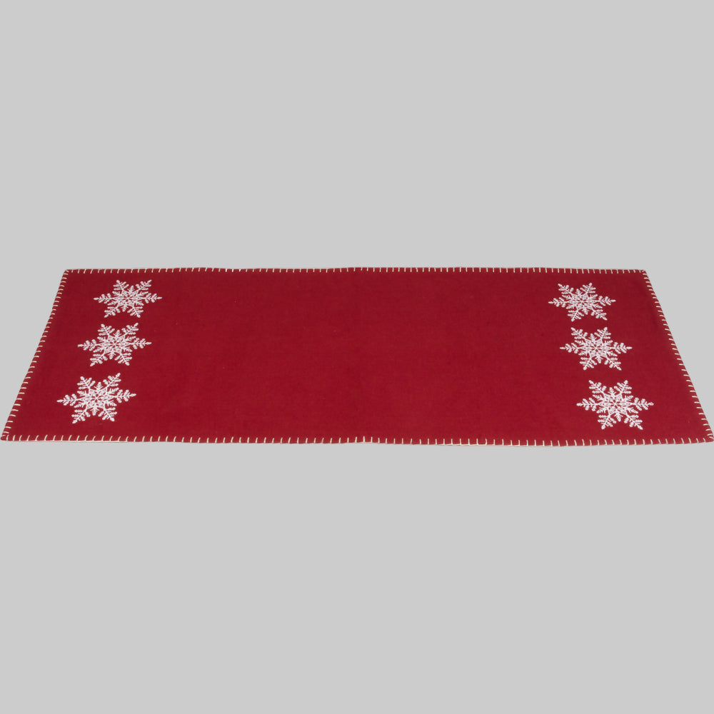 A red table runner with white snowflake embroidery on the ends, laid flat.