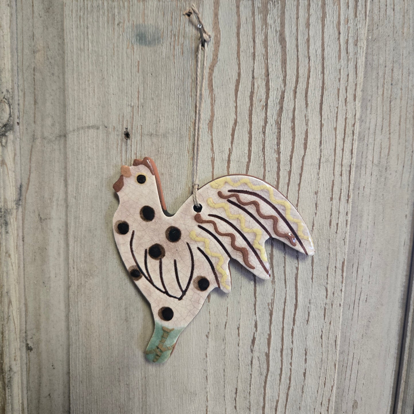 Pottery ornament in the shape of a hen with cream coloring and brown speckles