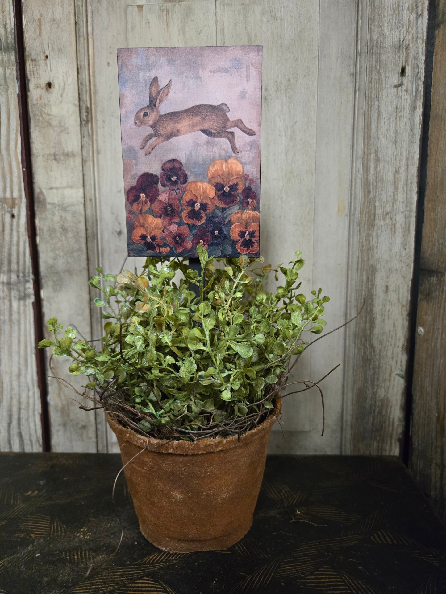 Potted plant on a wooden surface with a bunny plant poke