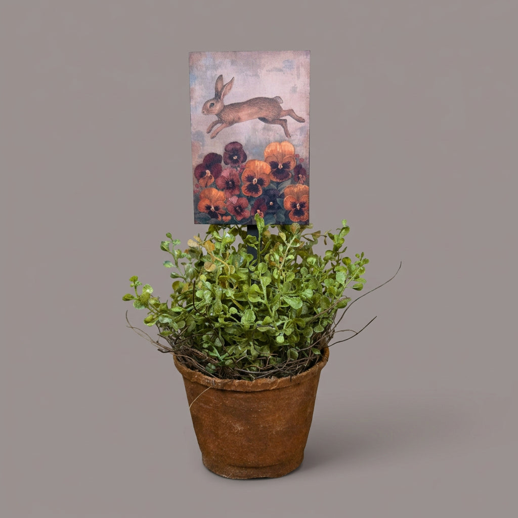 Potted plant on a wooden surface with a bunny plant poke