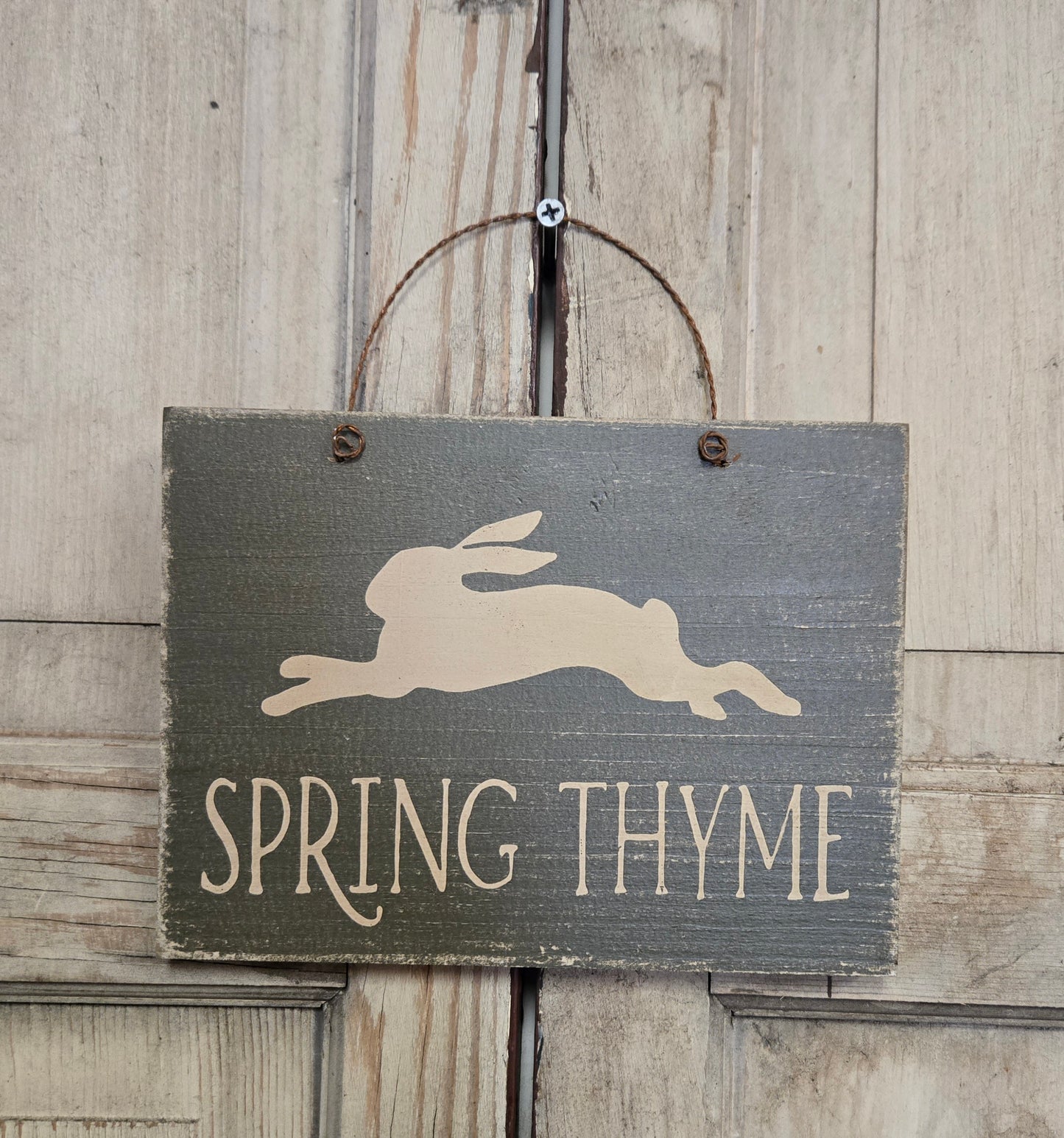 Wooden sign with a rabbit silhouette and 'Spring Thyme' text on a rustic wooden background