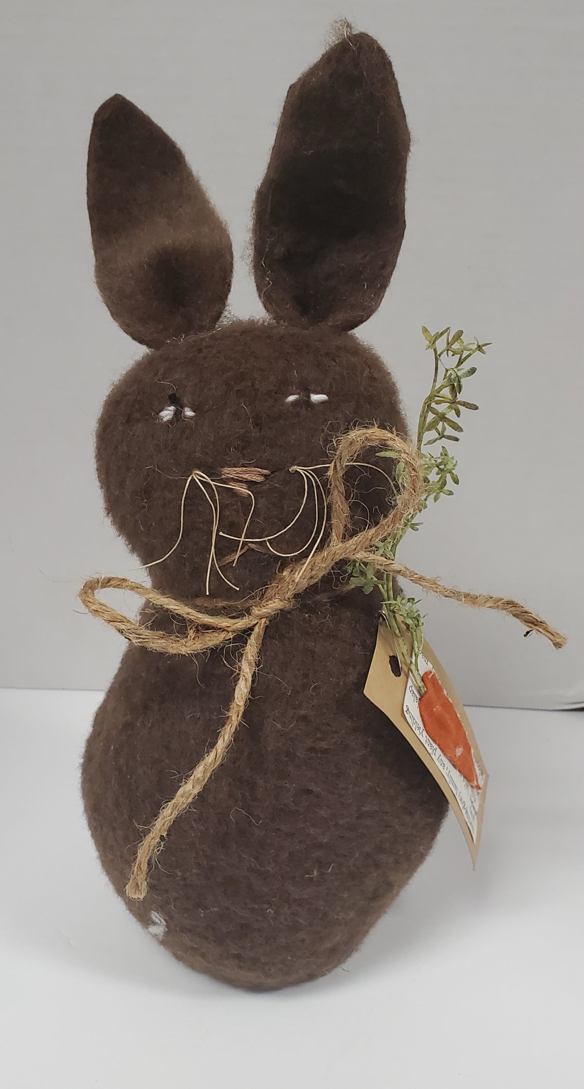 Brown felt bunny with twine and carrot on a white background