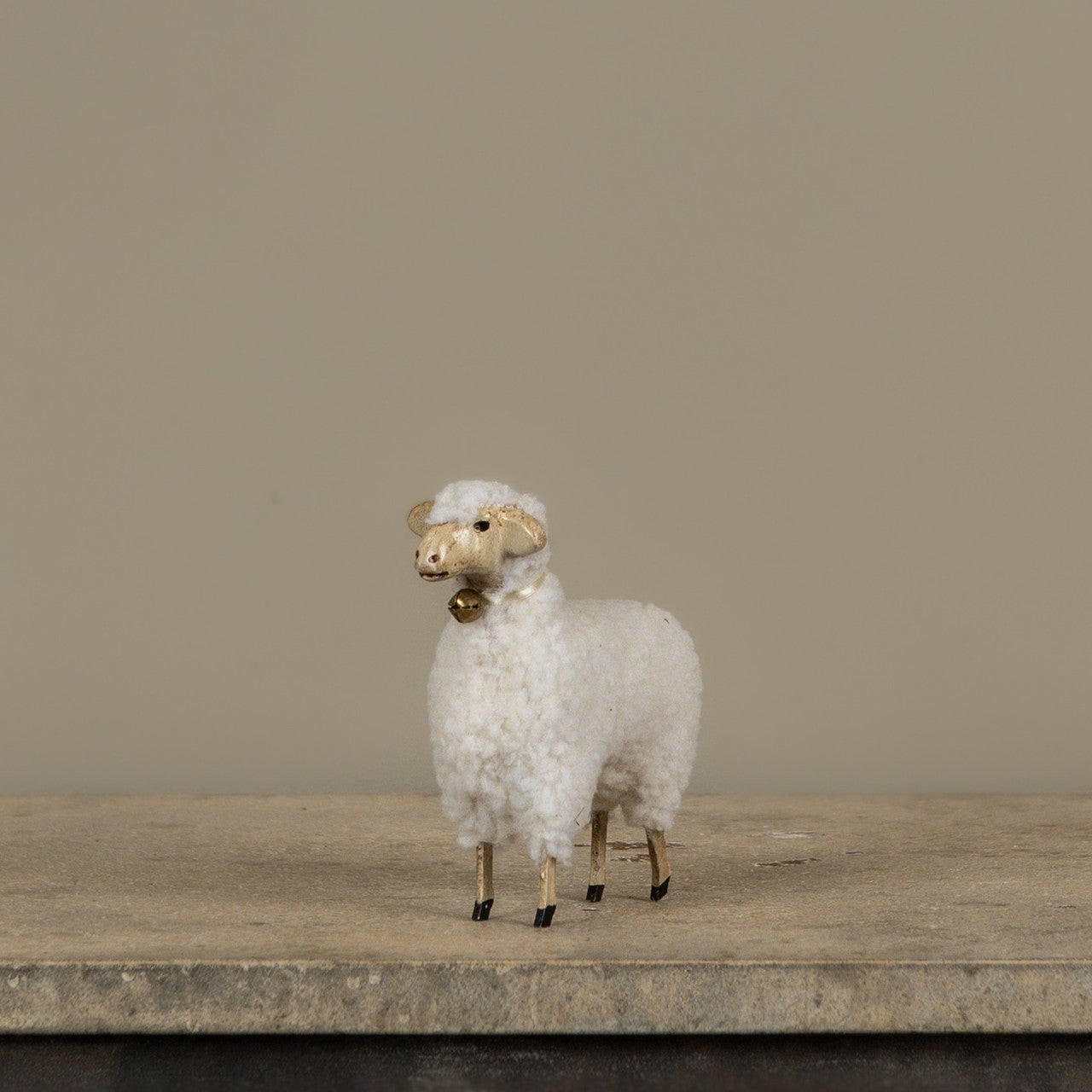 White sheep figurine on a wooden surface with a plain background
