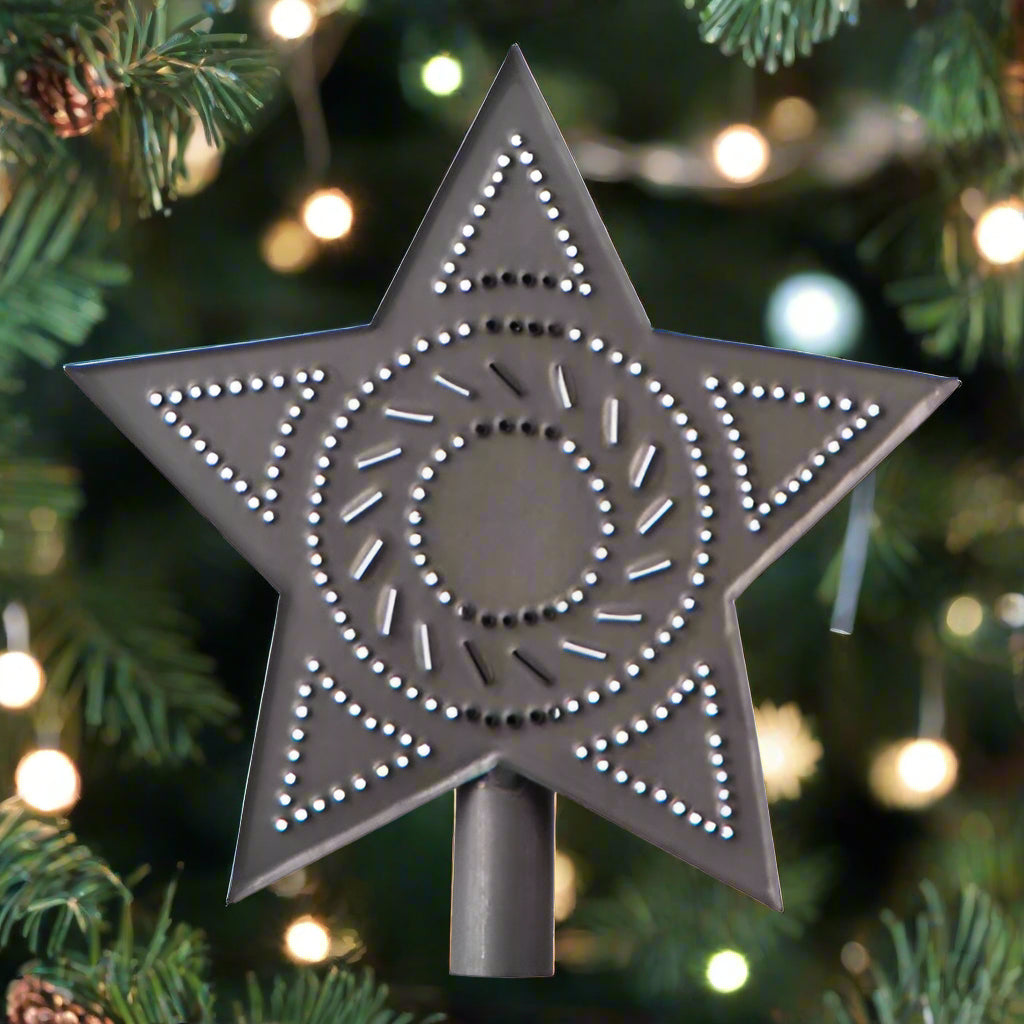 A Kettle Black star-shaped tree topper with a pattern of holes creating a starburst design on a black background.