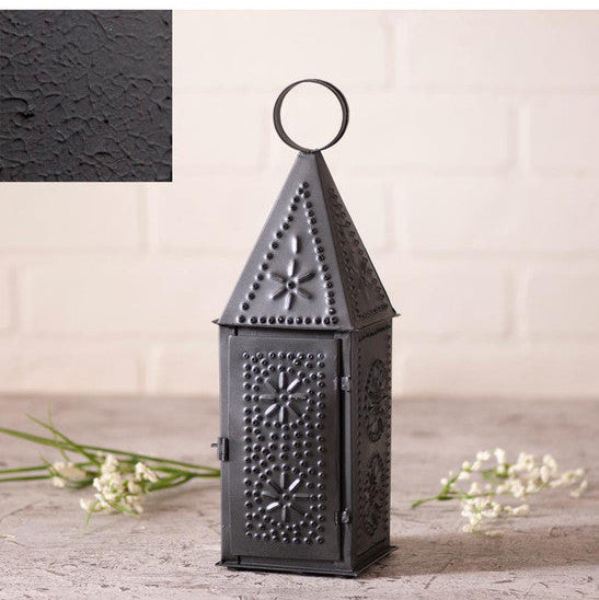 Textured black finish lantern on a light wooden surface with flowers.