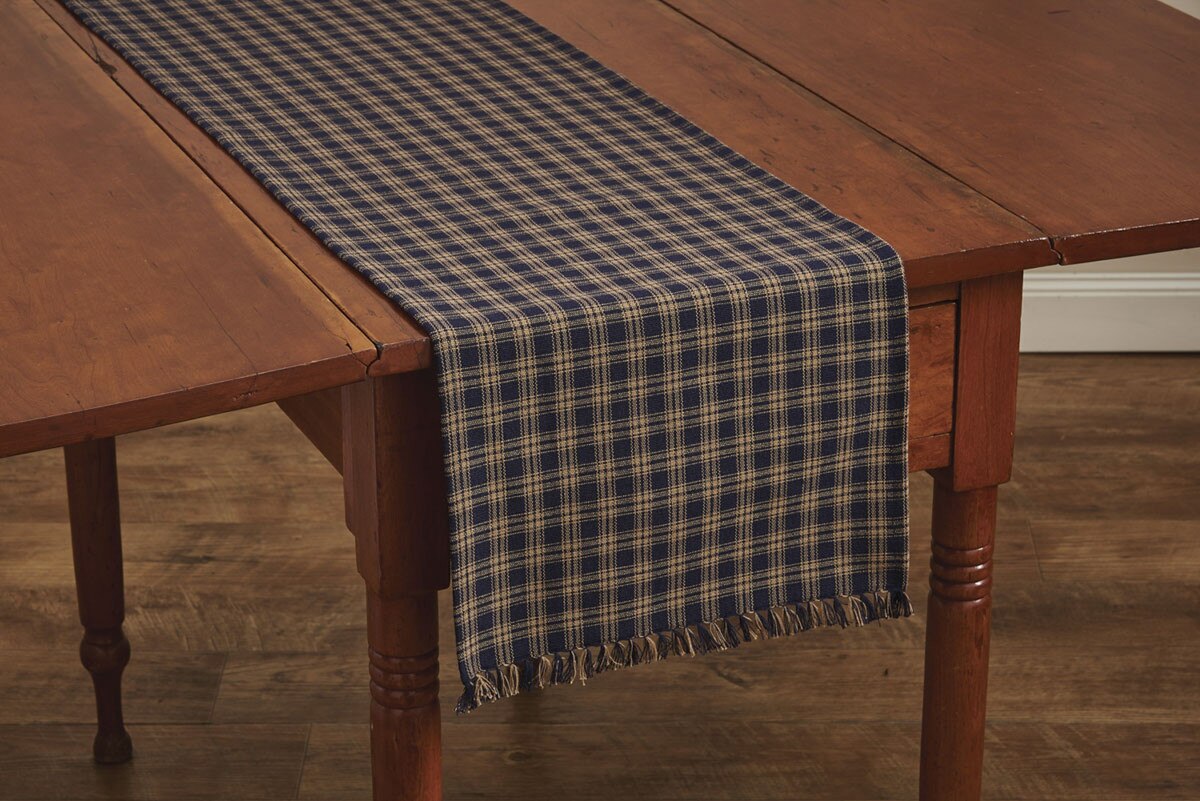 Wooden table with a blue plaid table runner on a wooden floor.