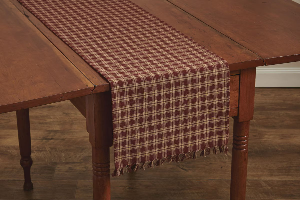 Wooden table with a plaid runner on a wooden floor