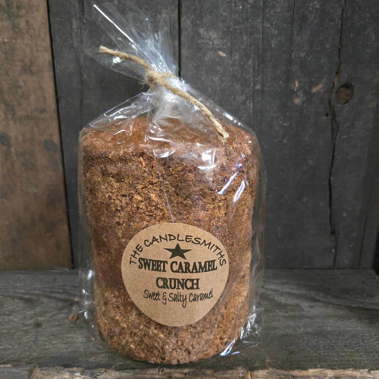 Wrapped sweet caramel crunch candle on a wood surface.