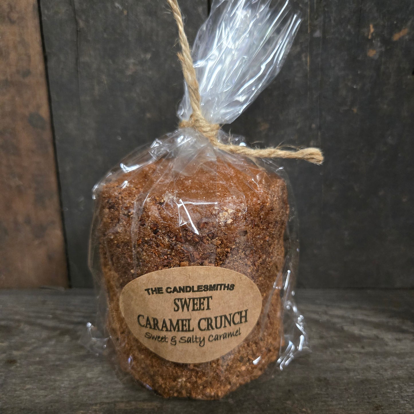 Wrapped Sweet Caramel Crunch candle on a dark surface.
