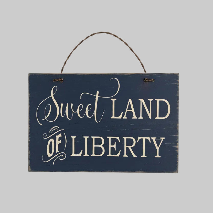 Wooden sign with 'Sweet Land of Liberty' text on a wooden background