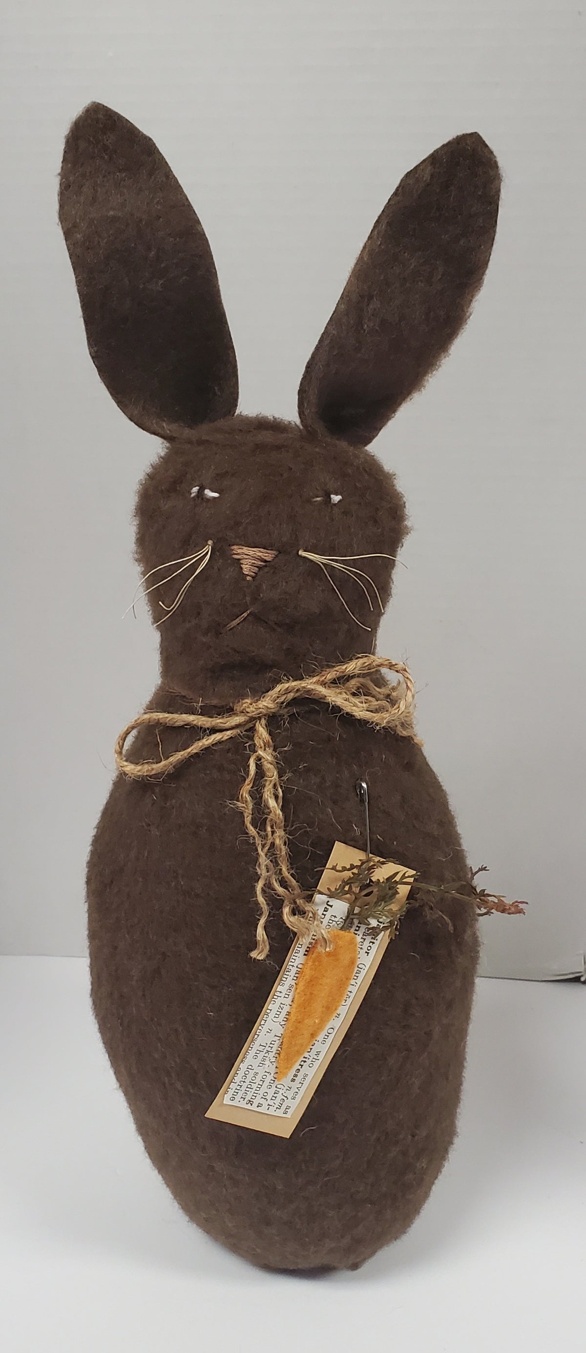 Brown stuffed bunny with a tag on a white background